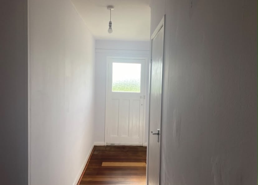 Renovated hallway with wood flooring and front door