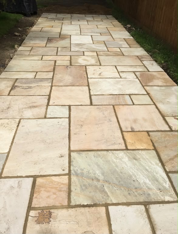Newly laid sandstone patio pathway alongside a lawn