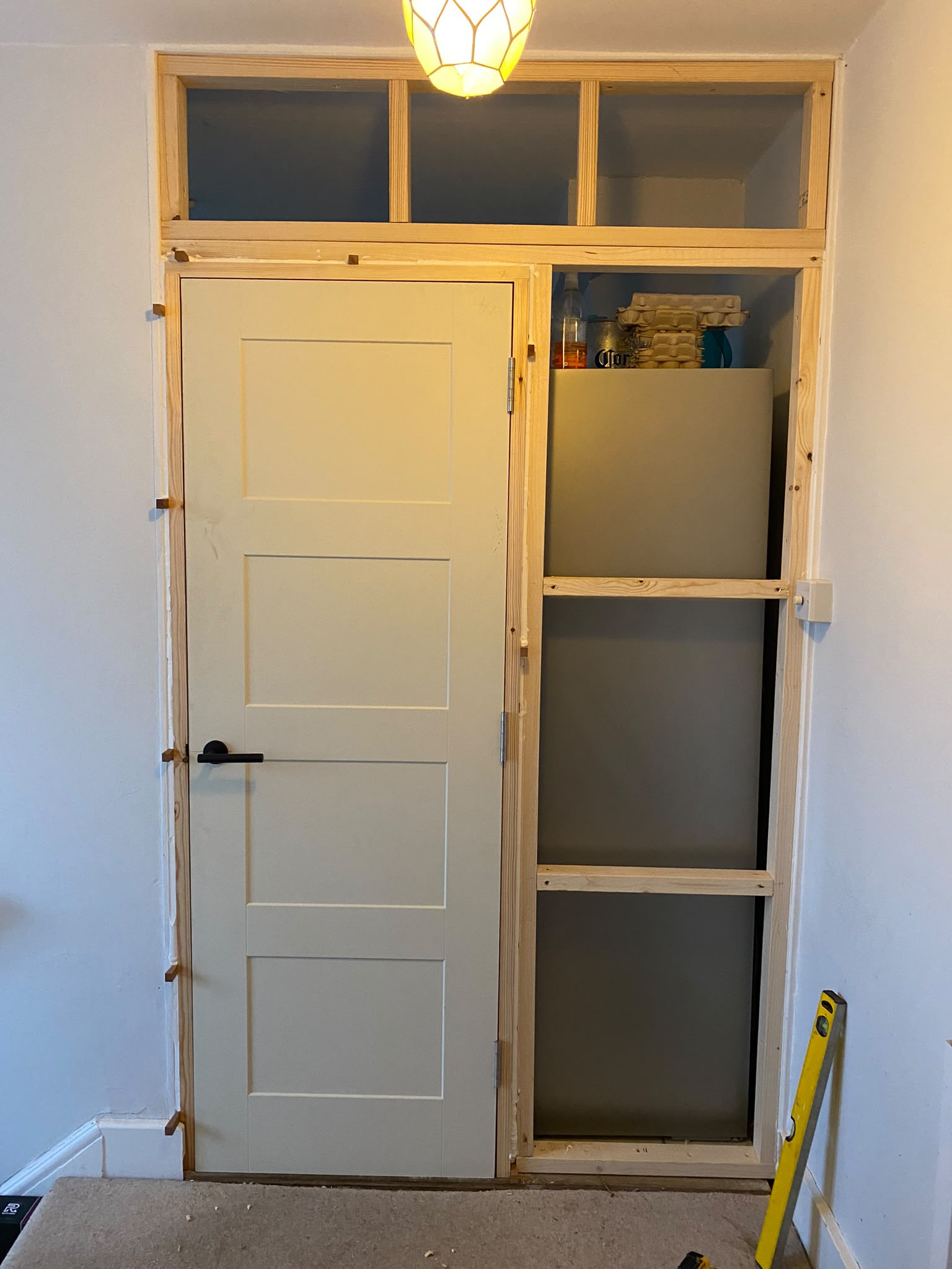 Fitted cupboard door hung with shelving frame alongside